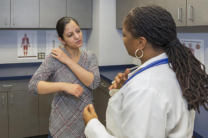 Patient discussing shoulder pain with her doctor Patient discussing shoulder pain with her doctor